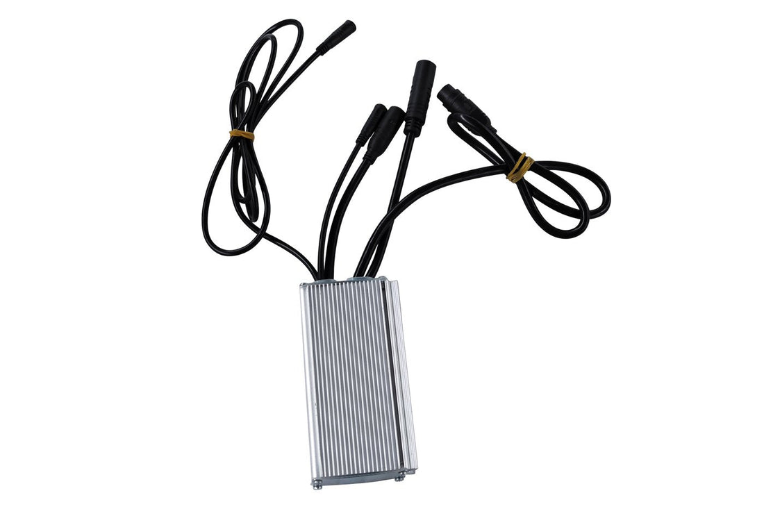 A silver finned aluminium e-bike controller lying on a white background, five black cable leads ending in waterproof bullet connectors fanning out from the top edge, three of them coiled and held with yellow ties