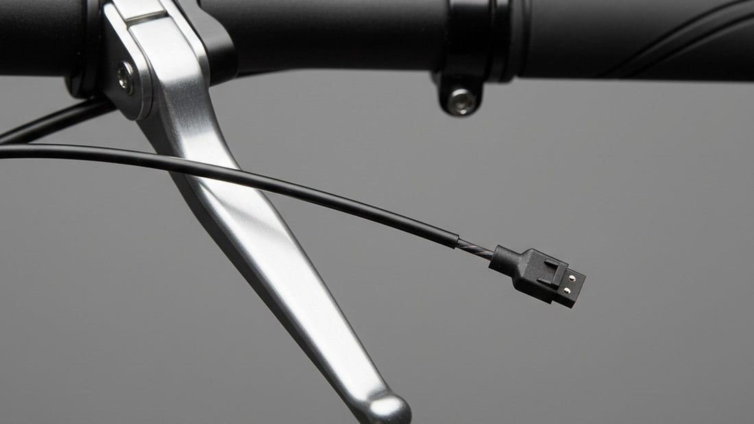 A close-up of an aluminium brake lever clamped on a black handlebar, with the brake cable and a thin sensor wire ending in a small two-pin connector, against a plain grey background.