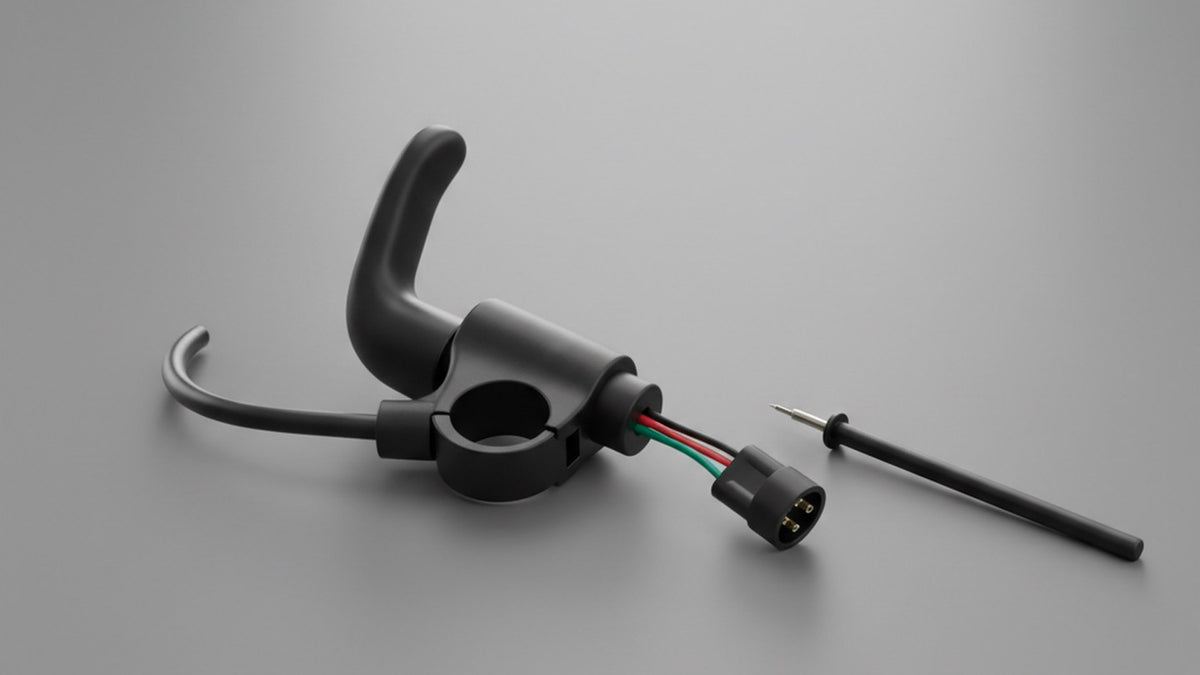 A black thumb throttle unit with its handlebar clamp, a three-wire pigtail in red, black and green ending in an unplugged three-pin connector, and a slim test probe resting beside it on a plain grey surface.