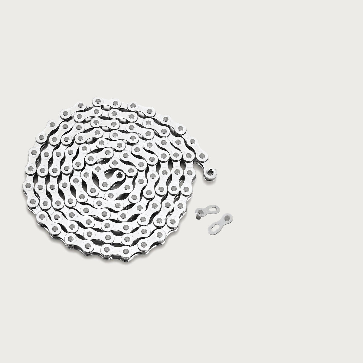 Silver bicycle chain coiled up next to two quick-link connectors